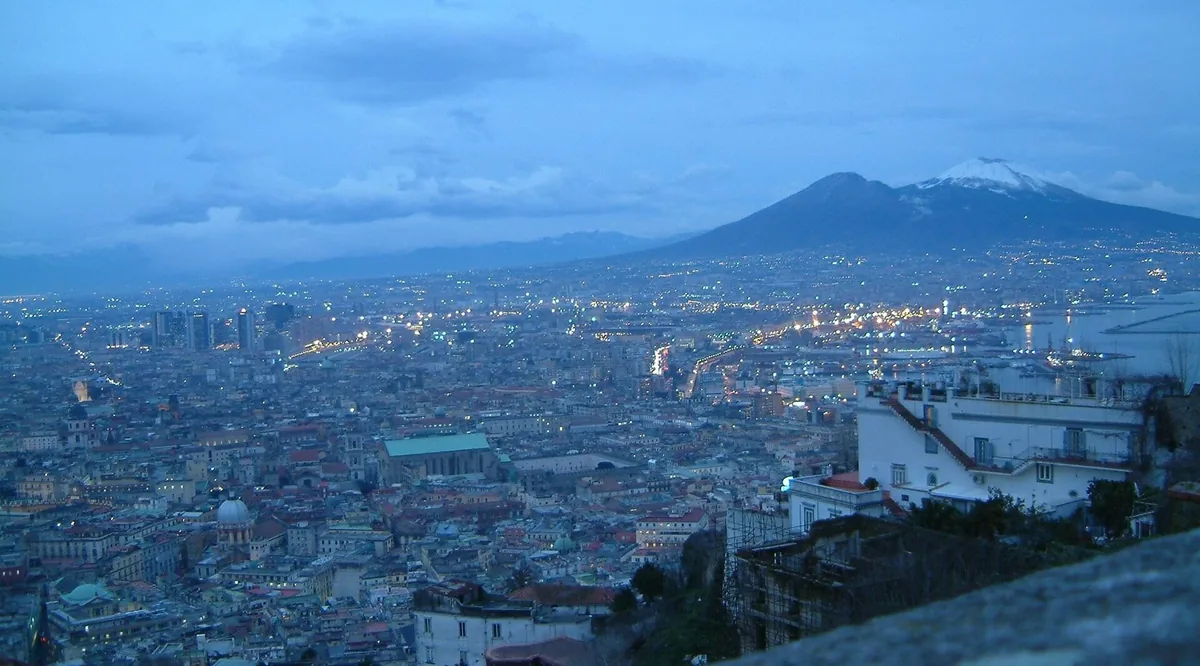 Naples' historic center at dusk from Castel Sant'Elmo, with snow-capped Vesuvius behind