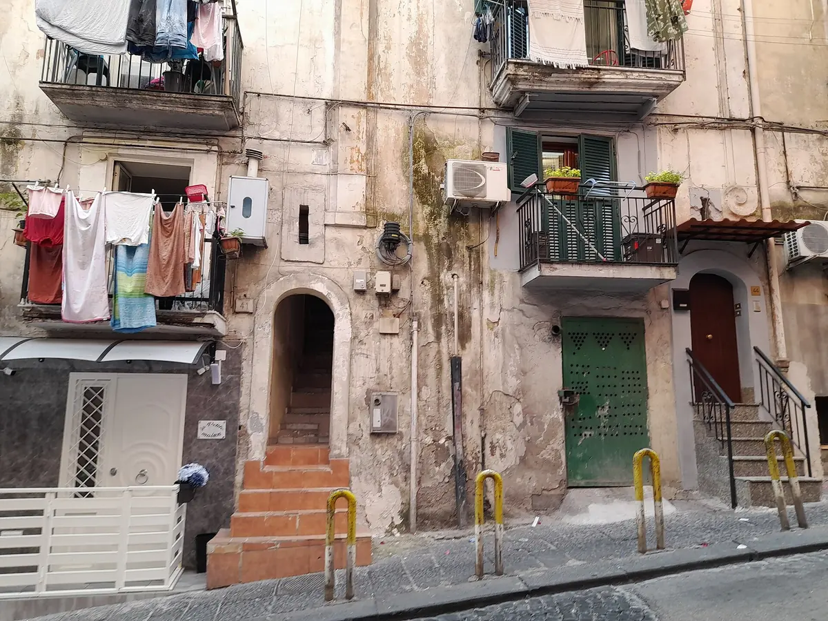 Linge étendu sur des balcons au-dessus de logements de plain-pied dans une ruelle pentue des Quartieri Spagnoli