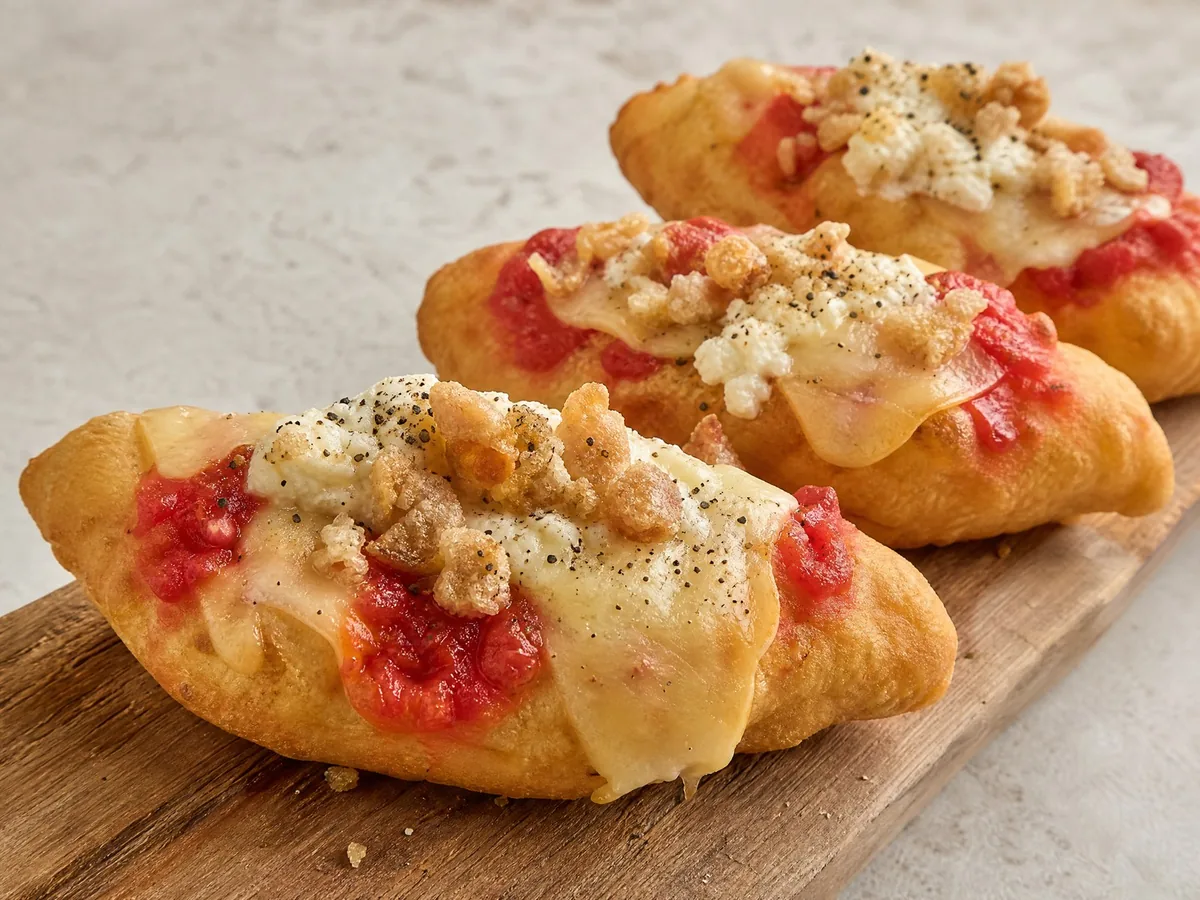Pizza fritta con cicoli, ricotta di bufala di fuscella, pepe, provola affumicata e pomodoro, servita in tre pezzi