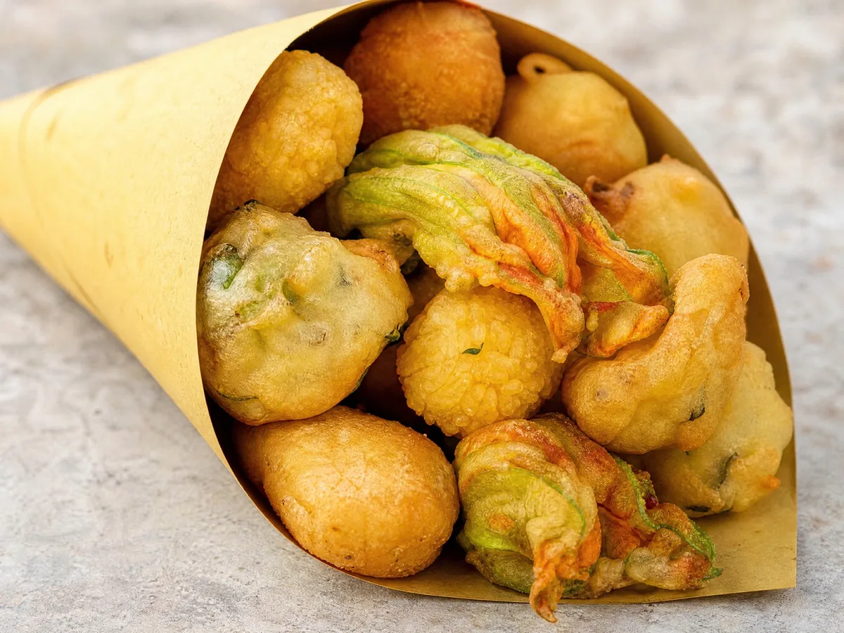 Ein Papiertüten-Kegel mit gemischtem frittiertem Streetfood: Reisbällchen, Croquettes und Teigfritters