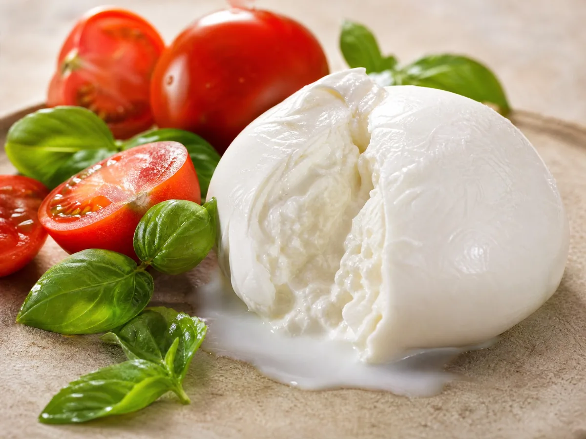 Ein aufgeschnittener Büffelmozzarella-Ball mit Tomaten und Basilikum