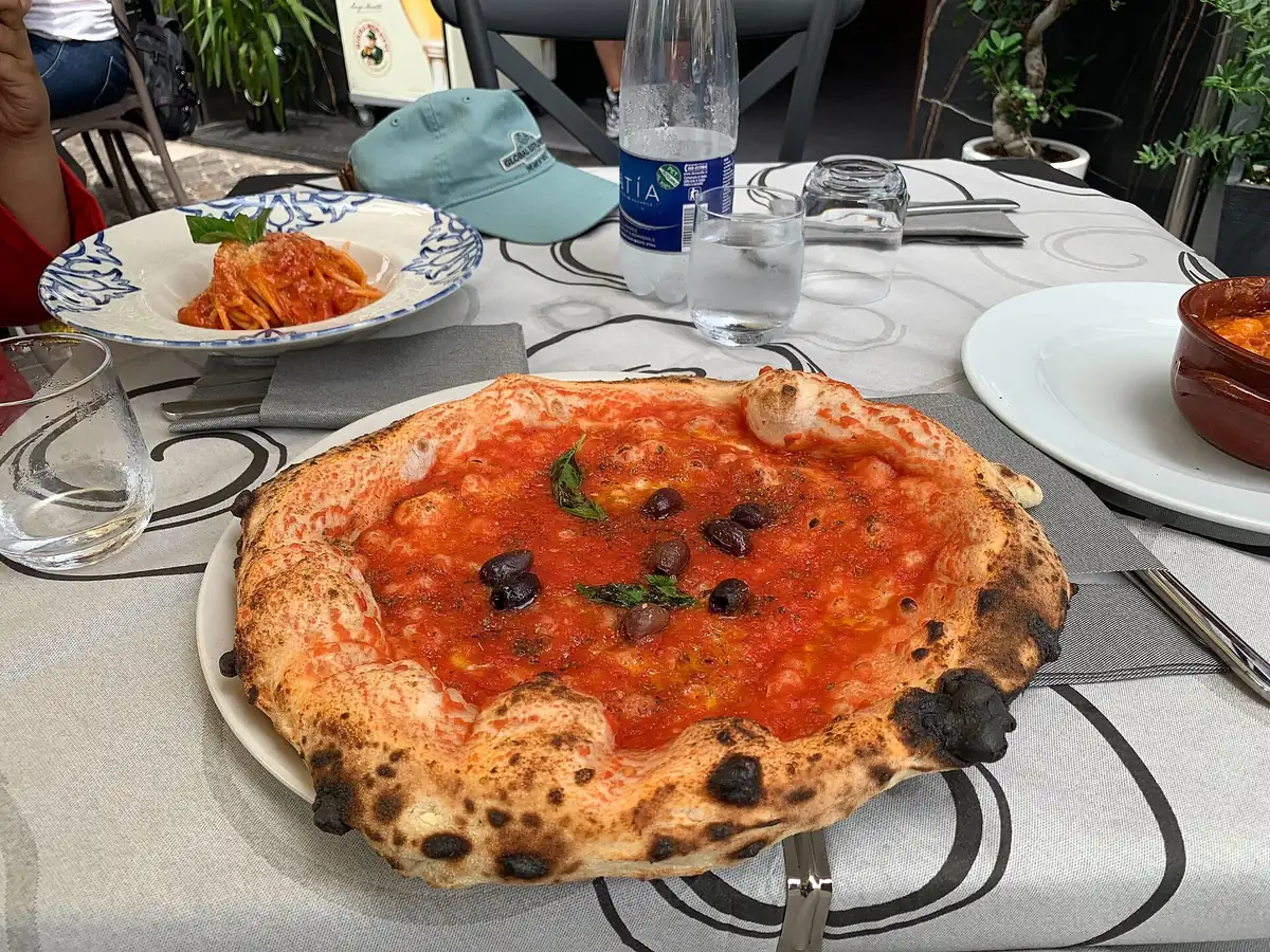 Une pizza napolitaine aux olives sur une table de restaurant