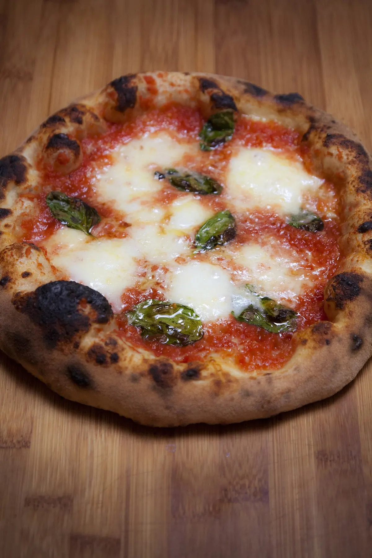 A blistered Neapolitan-style margherita with basil on a wooden board