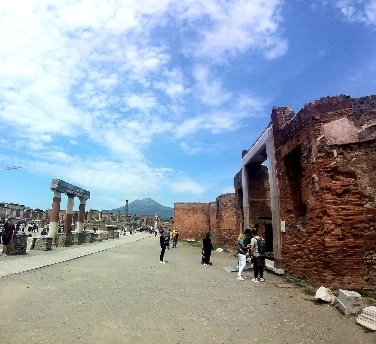 Visitors in the Forum of Pompeii with Vesuvius in the distance