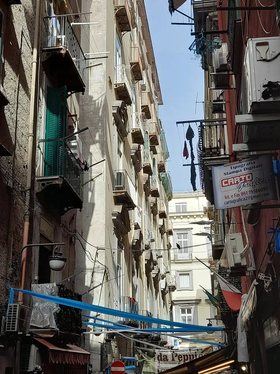 Rue étroite des Quartieri Spagnoli avec des balcons et des enseignes de magasins
