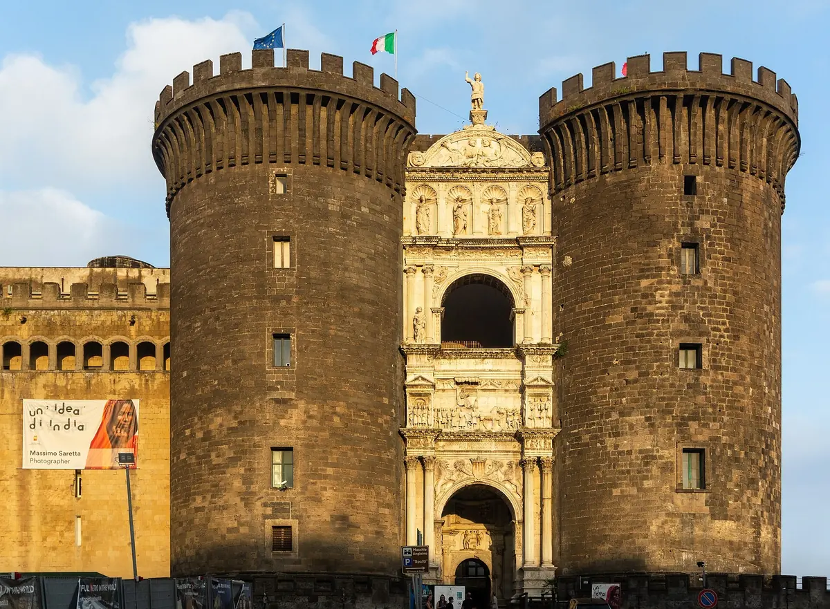 Arc de triomphe en marbre blanc encadré par les tours rondes sombres du Castel Nuovo à Naples