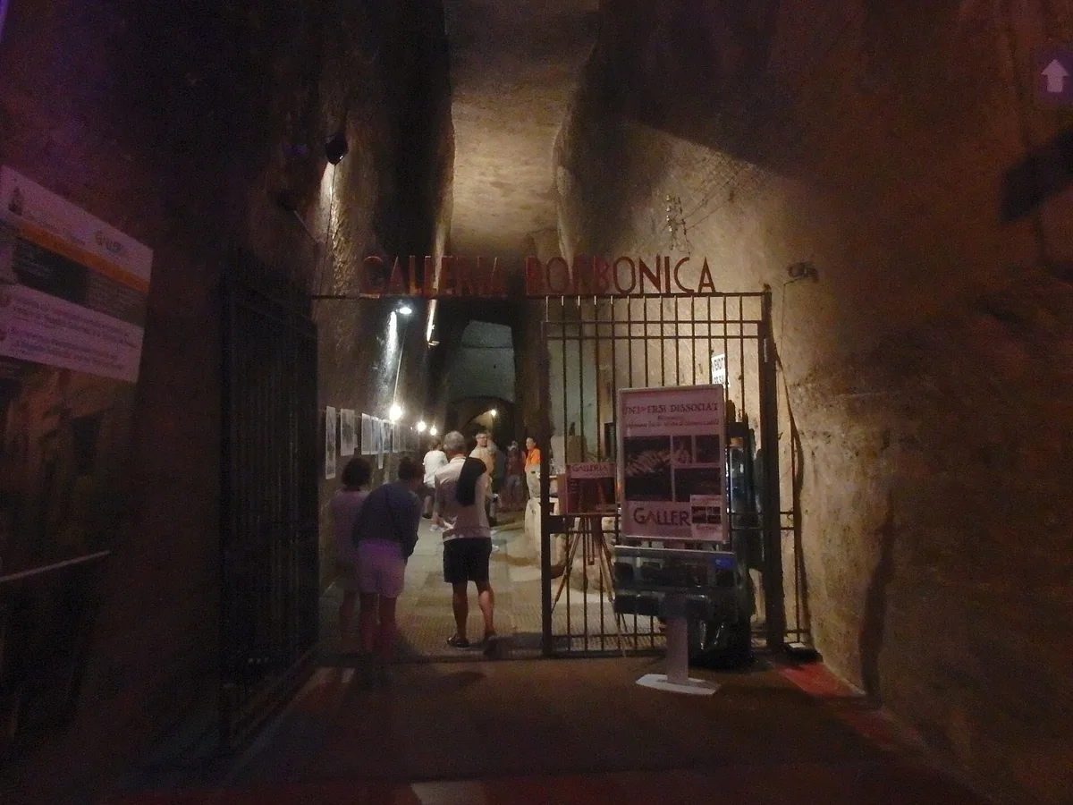 Visiteurs à l’entrée grillagée du tunnel de la Galleria Borbonica creusé dans le tuf
