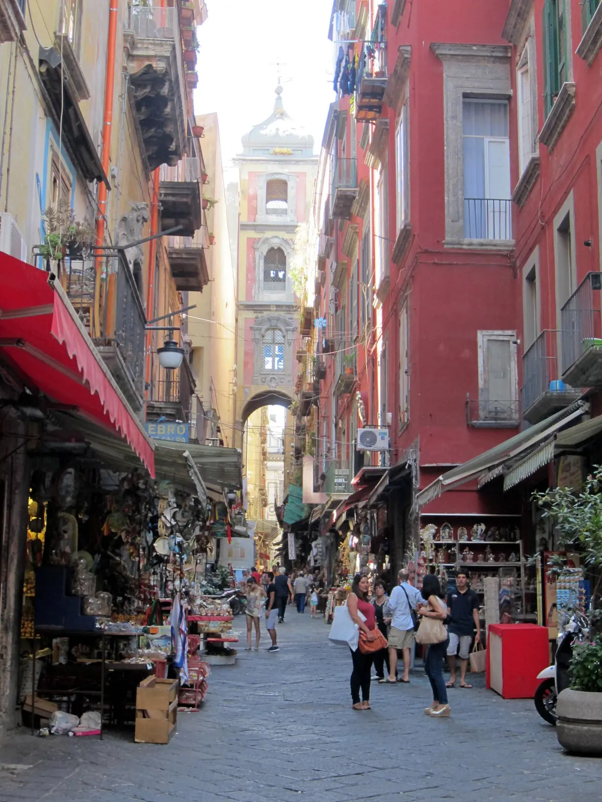 Des acheteurs parmi les étals de crèches sur Via San Gregorio Armeno, l'arche de la tour du clocher en arrière-plan