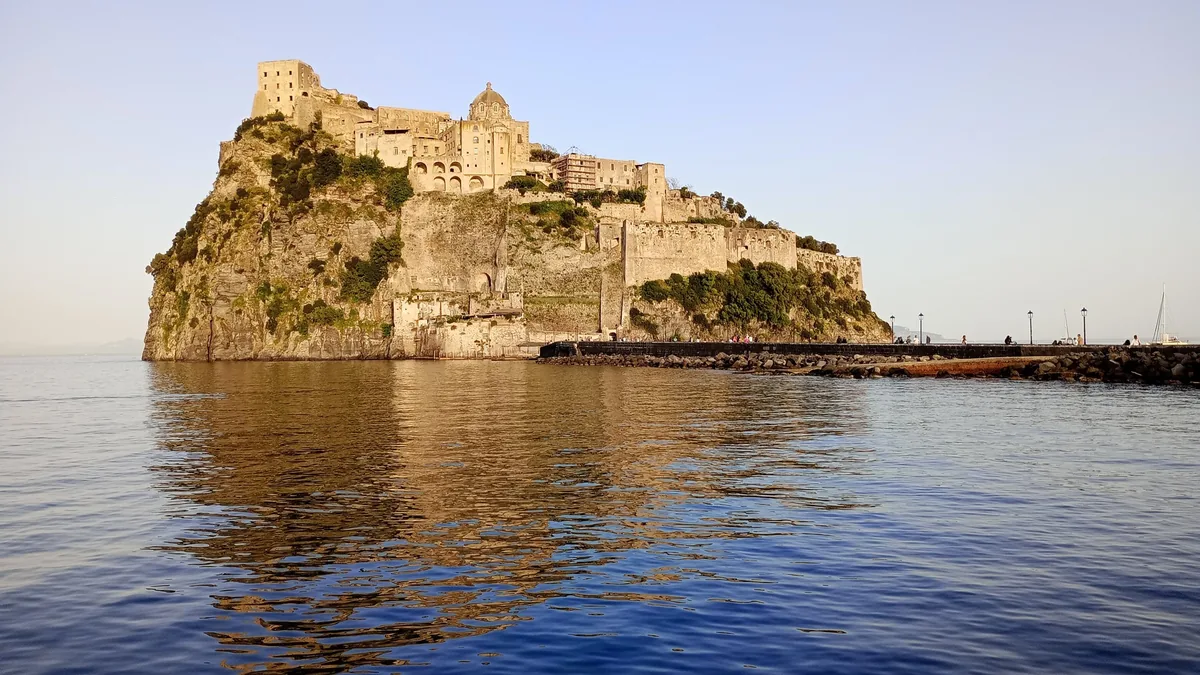 Das Castello Aragonese auf seiner Felsinsel vor Ischia Ponte, das sich im Meer spiegelt