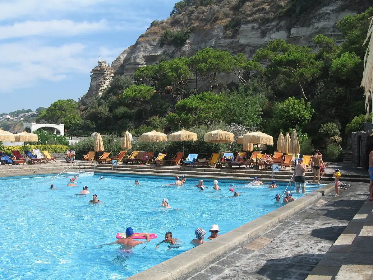 Badende in einem Thermalbecken der Giardini Poseidon auf Ischia unter grünen Klippen