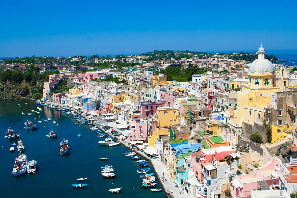 Colorful houses of Marina Corricella and a domed church above Procida's harbor