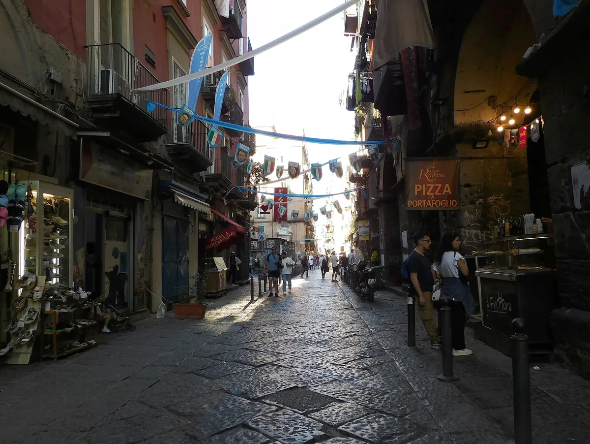 La Via dei Tribunali dans le centre ancien, bordée de magasins, de pizzerias et de bannières suspendues